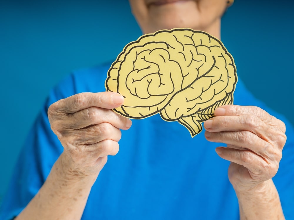 Une personne âgée tient une image de cerveau dans ses mains pour illustrer la maladie de Parkinson