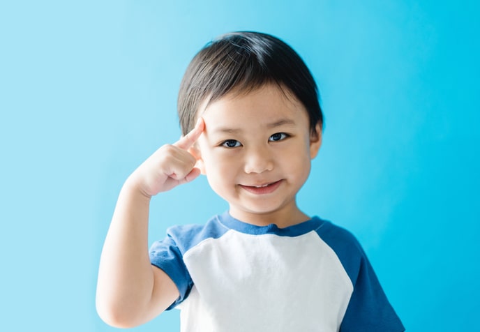 Un jeune enfant illustre le raisonnement en pointant sa tête